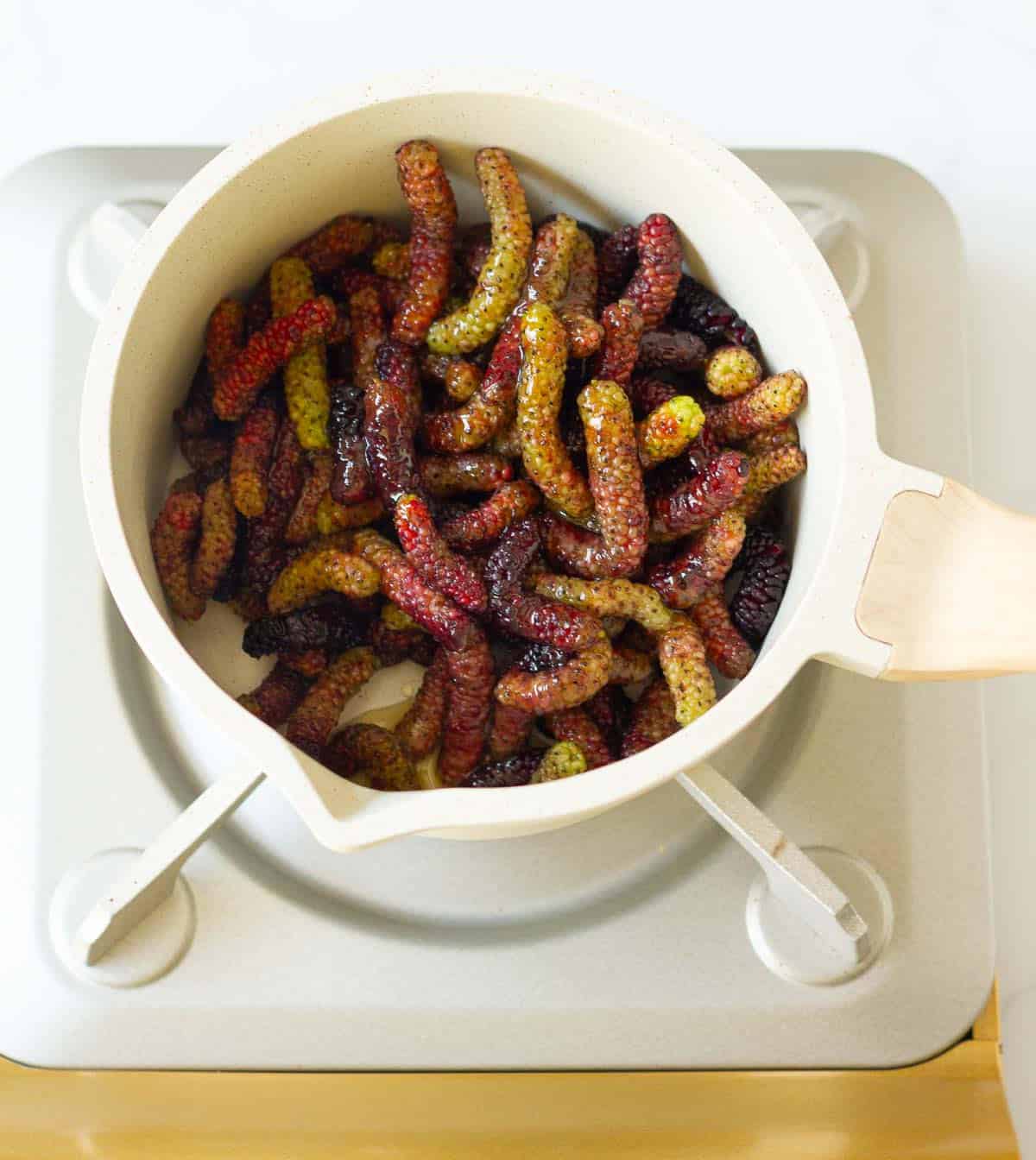 Mulberries with honey and water in a saucepan.