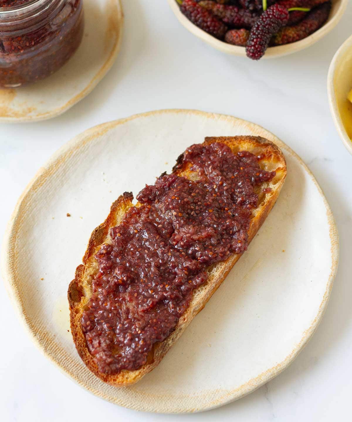 Jam spread on top of toast on a small plate.