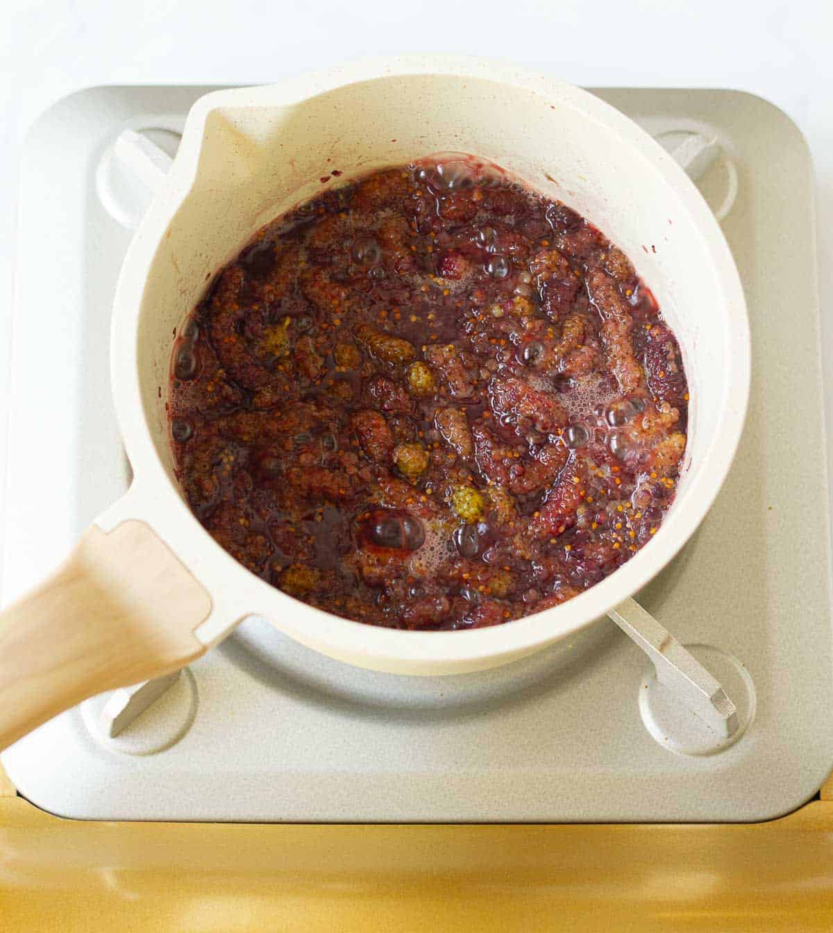 Bubbling mulberry jam mixture in a saucepan.