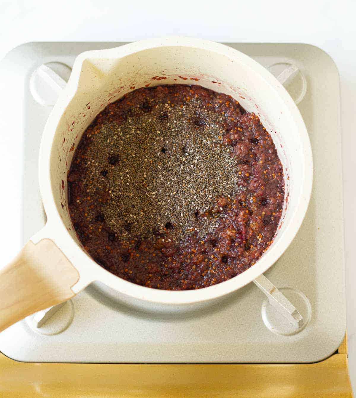 Chia seeds on top of the soft, cooked mulberries in a saucepan.