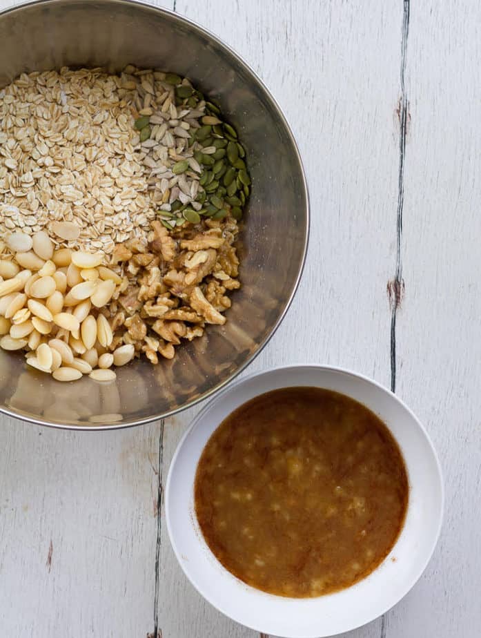 dry ingredients for granola in a large bowl and wet ingredients in a small white bowl.