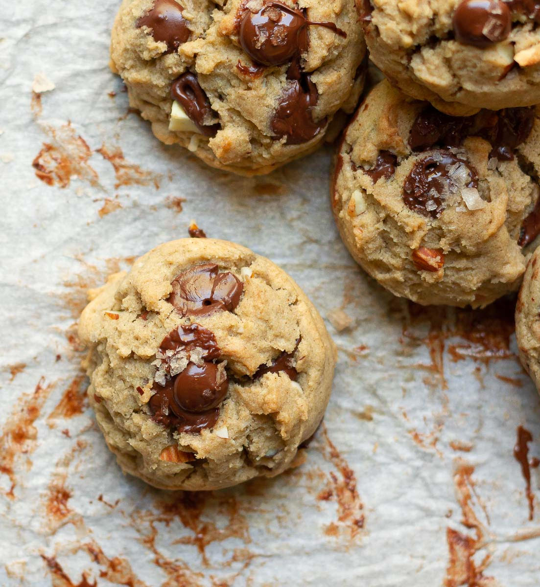 Chocolate chip cookie with sea salt on top on parchment paper.