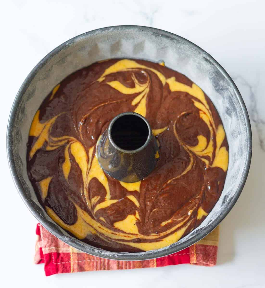 swirled pumpkin and chocolate batters in the bundt cake tin