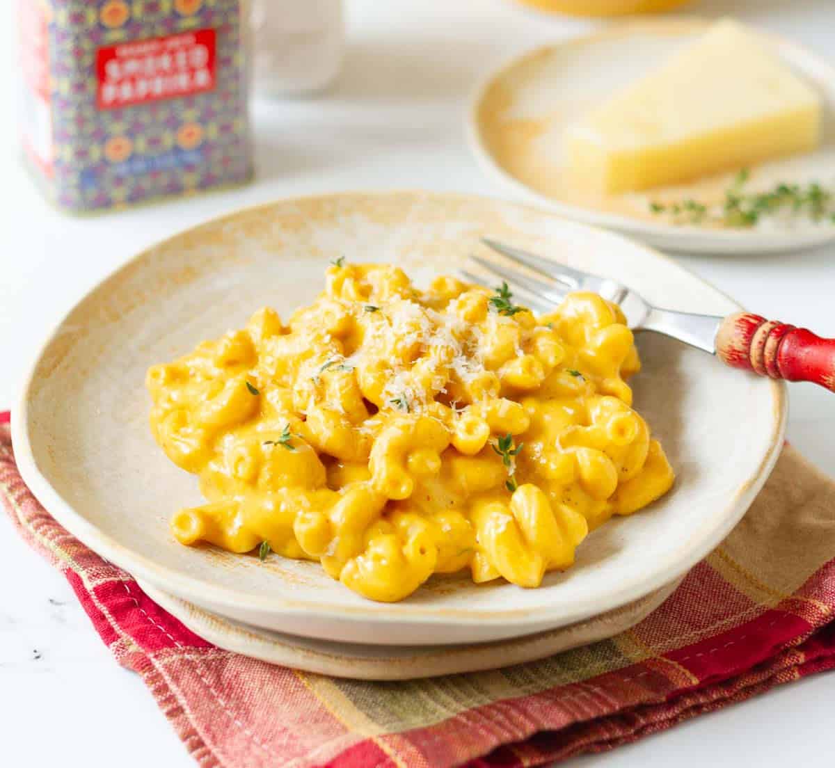 A plateful of pumpkin mac n cheese with a fork and ingredients around.