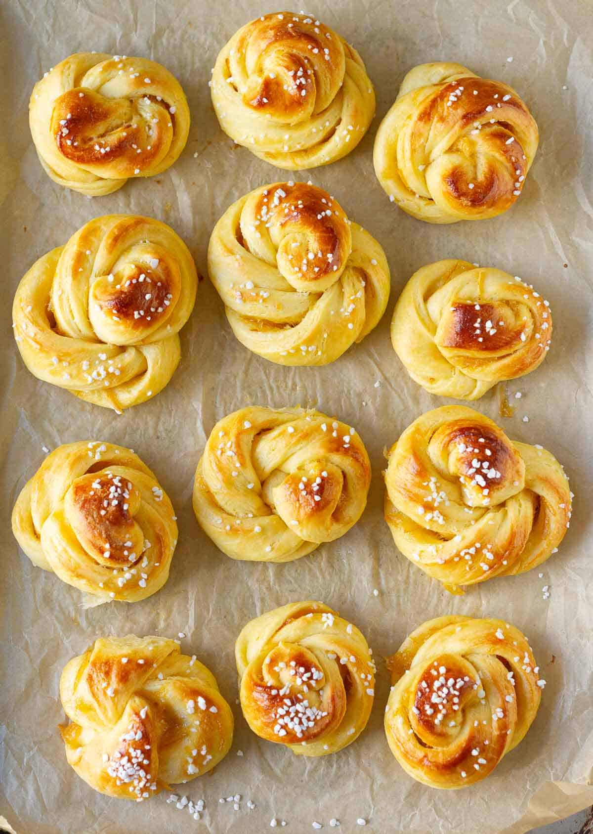 Baked orange brioche rolls on a parchment paper lined tray.
