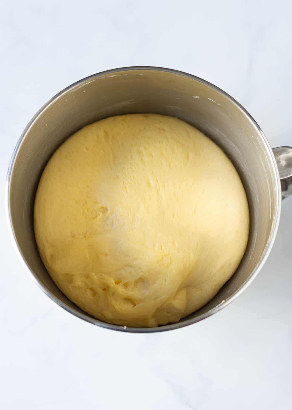 Proofed brioche dough in a stand mixer bowl.