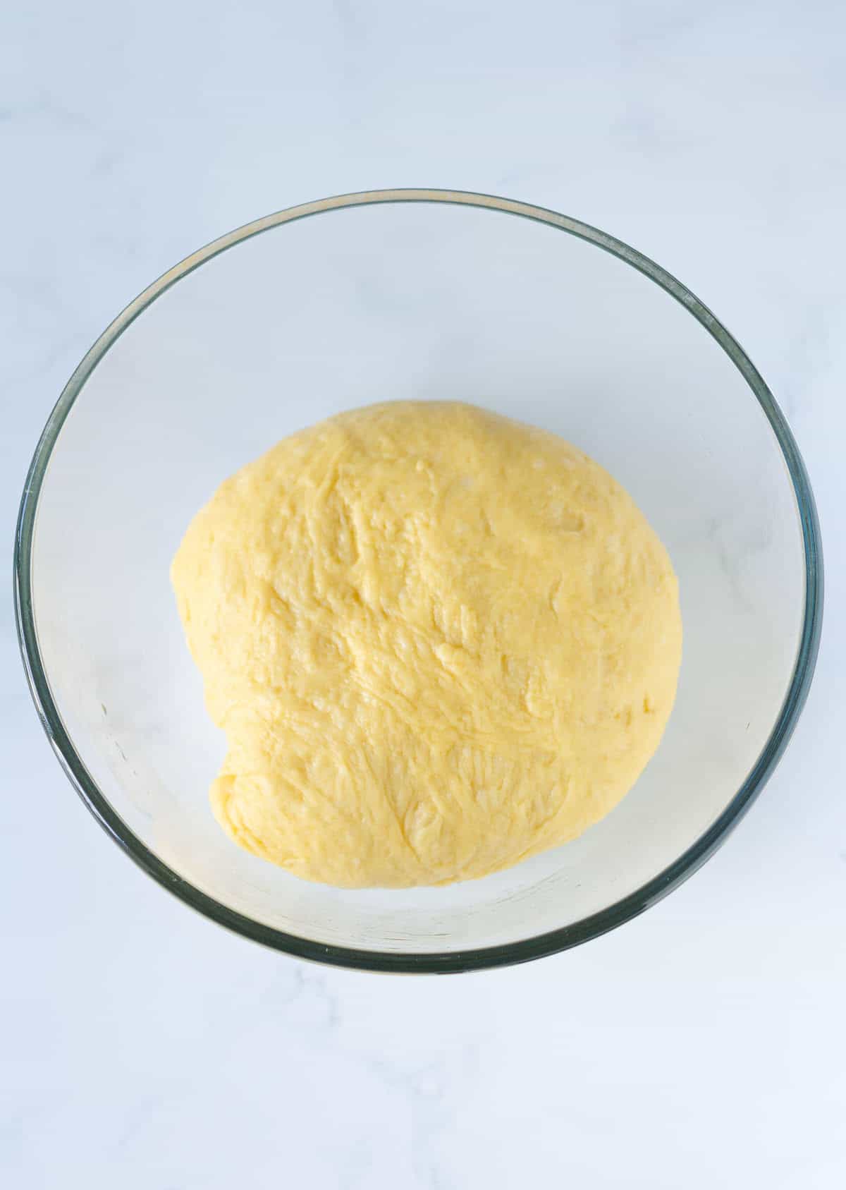 Brioche dough in a glass mixing bowl.