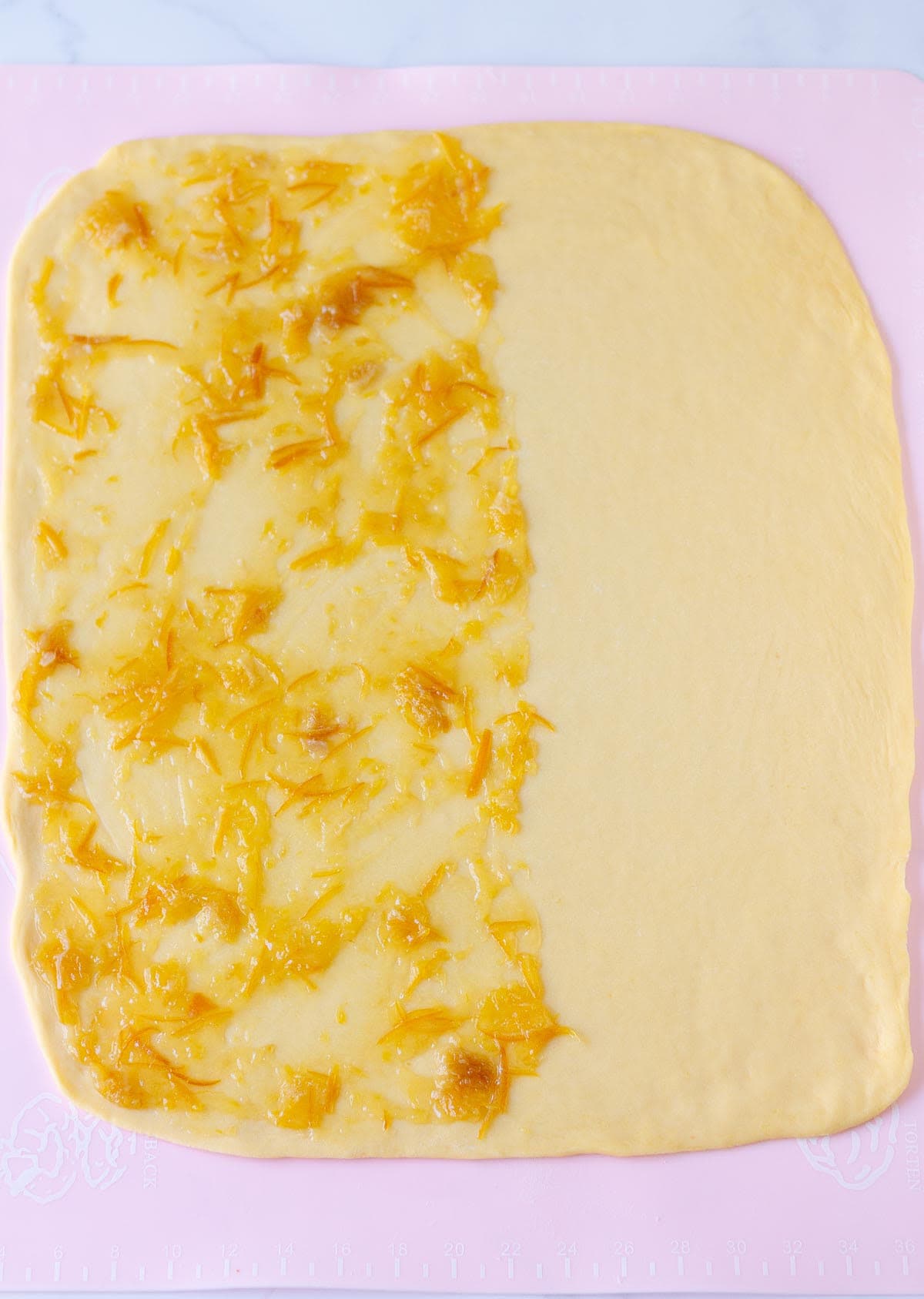 Dough rolled out into a rectangle with marmalade on half of the dough.