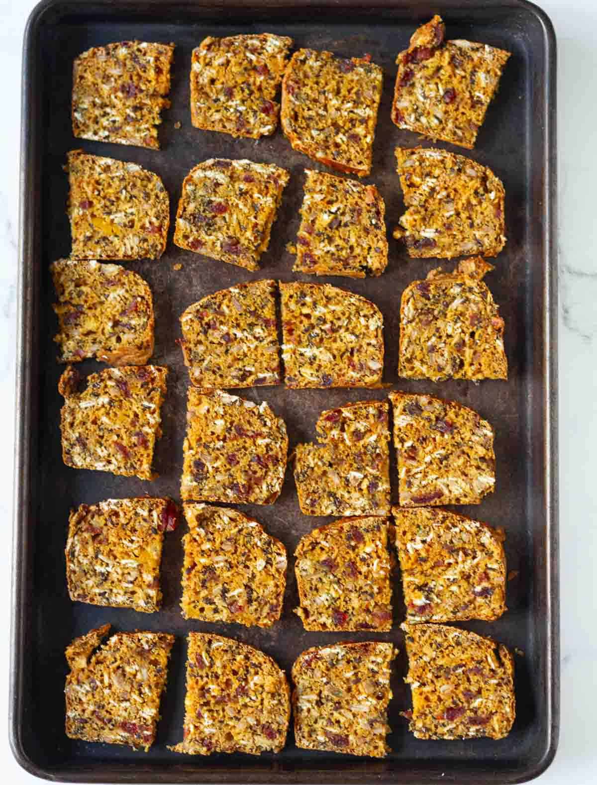 sliced crackers on a black baking tray.