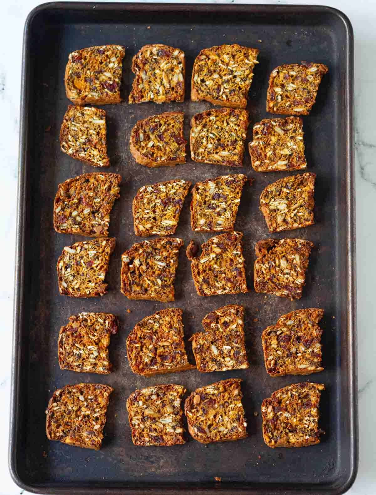 baked pumpkin cranberry crackers on a black baking tray.