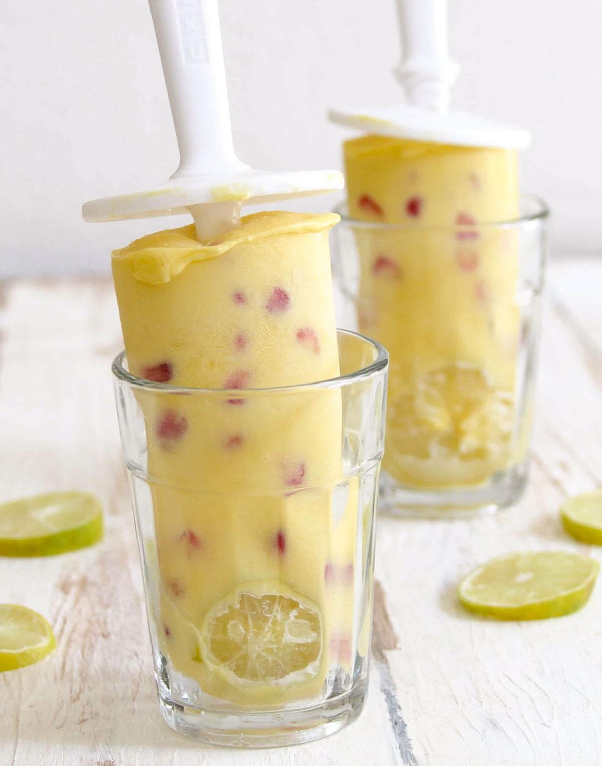 2 Fruit popsicles standing in glasses.