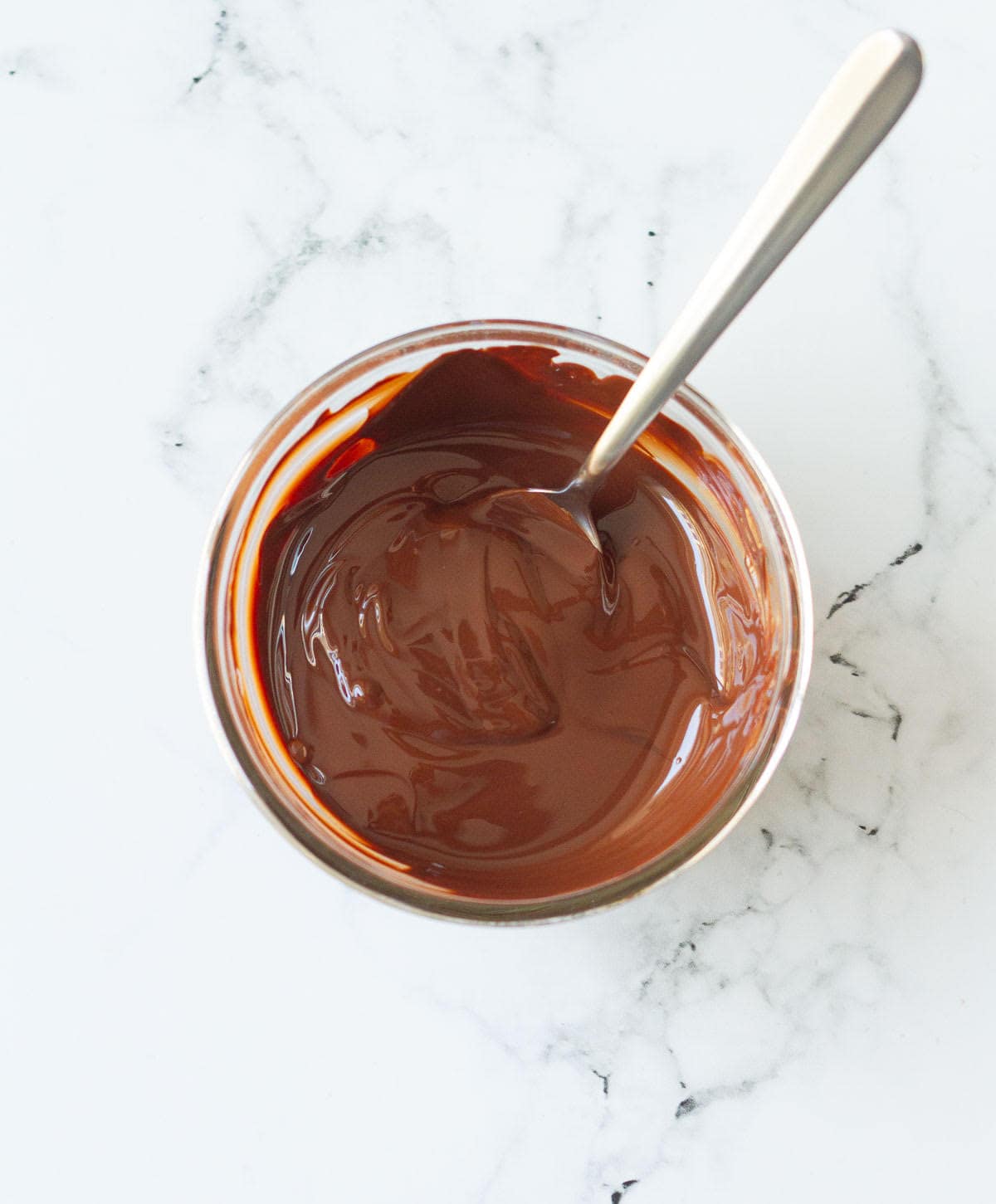 melted chocolate with a spoon in a glass bowl.
