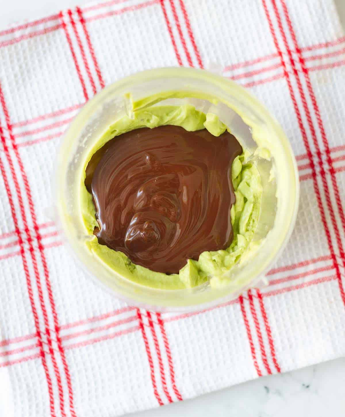 melted chocolate on top of avocado mixture in a blender jar.