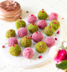 Coconut almond bliss balls with pistachio and pink colored coconut coating.