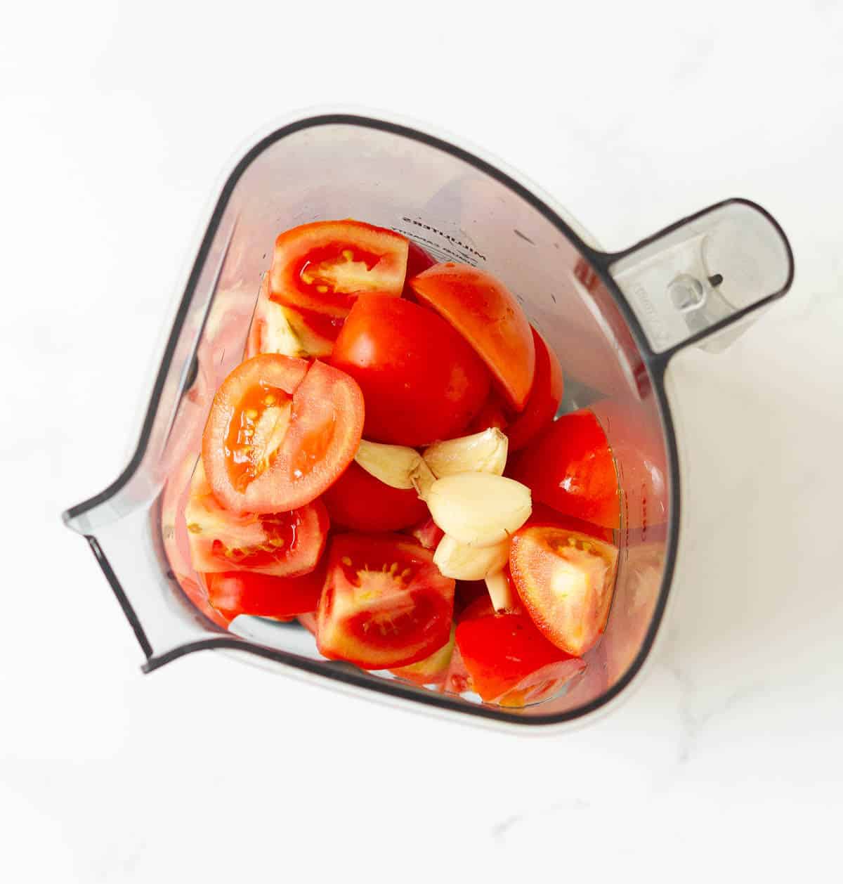 Chopped up tomatoes and garlic in a blender jar.