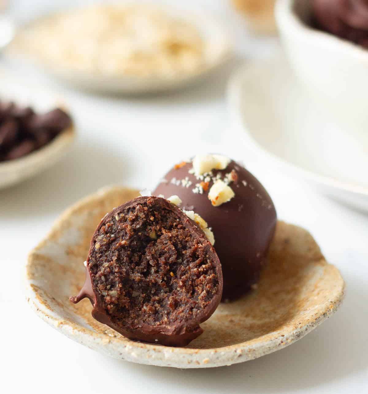 2 protein balls on a small plate with one half eaten to show the texture.
