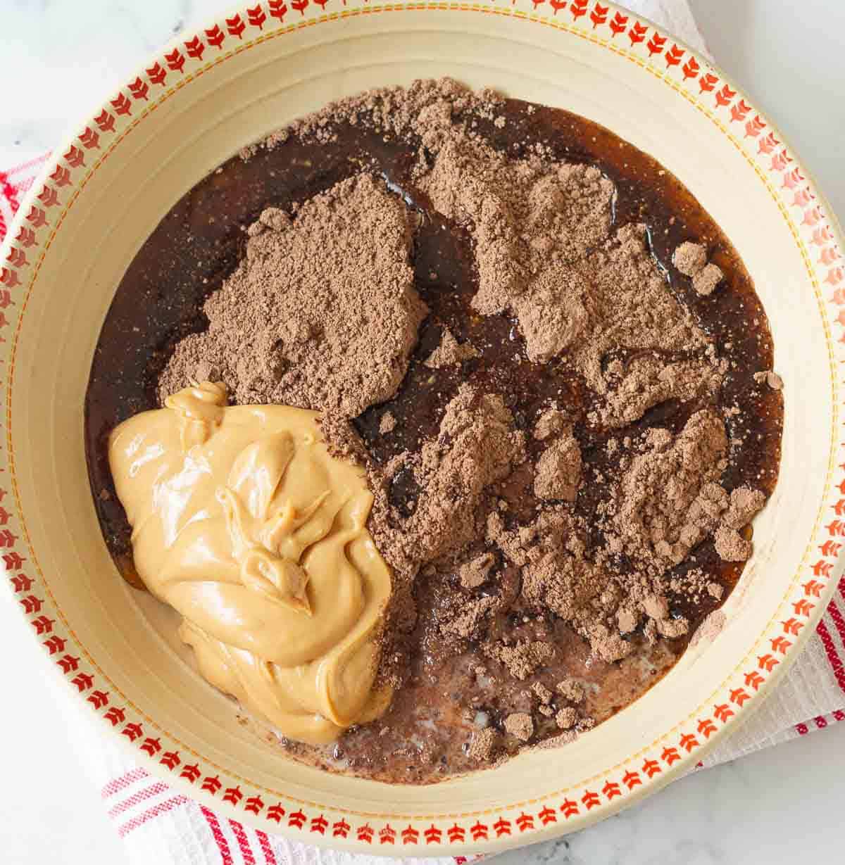 Peanut butter, oil,maple syrup on top of dry ingredients in a mixing bowl.
