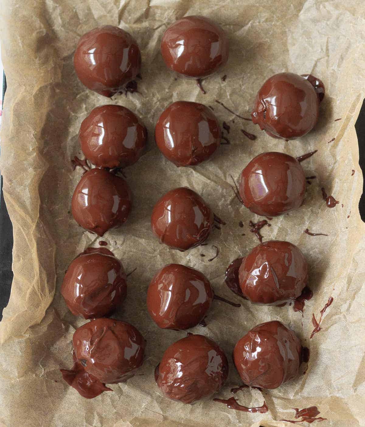 chocolate energy balls dipped in melted chocolate on parchment paper.