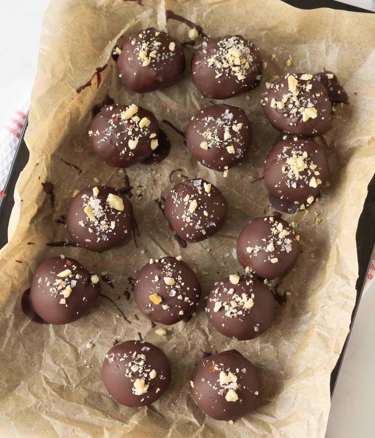 Protein balls topped with peanuts and sea salt on parchment paper.