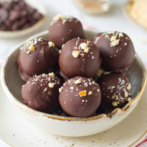 peanut chocolate protein balls topped with peanuts and seasalt in a small bowl.