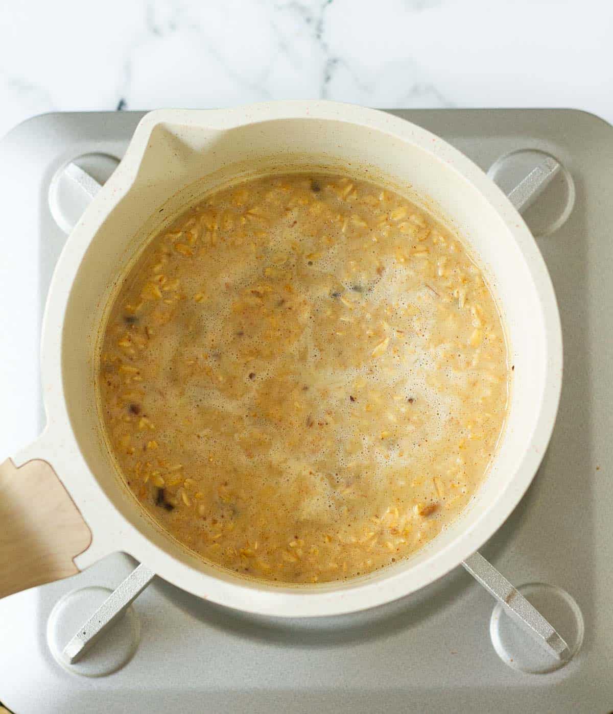 oats, milk, water, dates in a saucepan on a stove.
