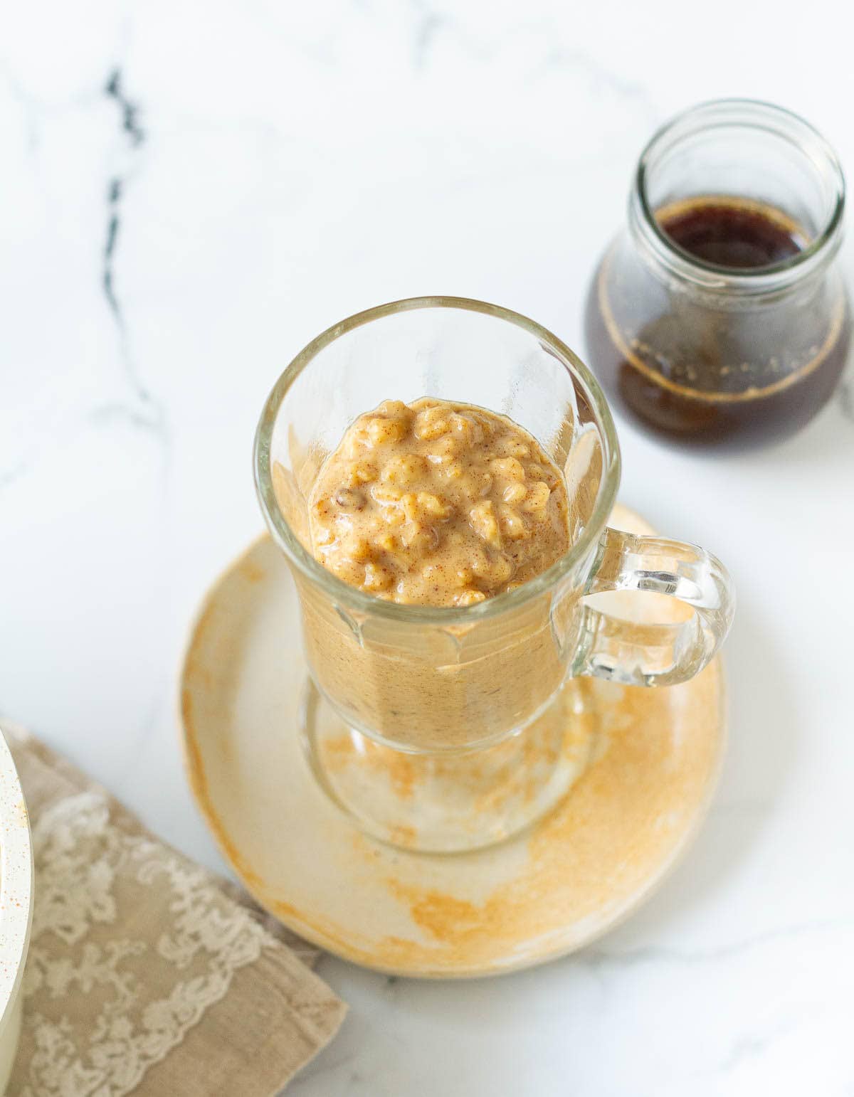 oatmeal in a glass mug on a small plate.