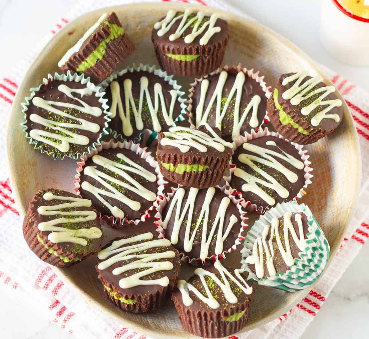 Chocolate matcha cups drizzled with white chocolate in a plate.