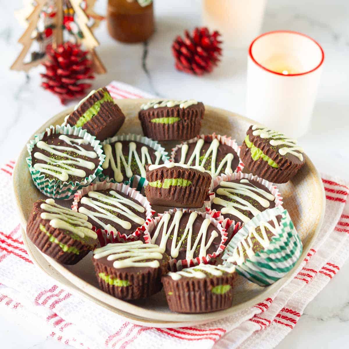 White chocolate drizzled chocolate matcha cups on a plate.