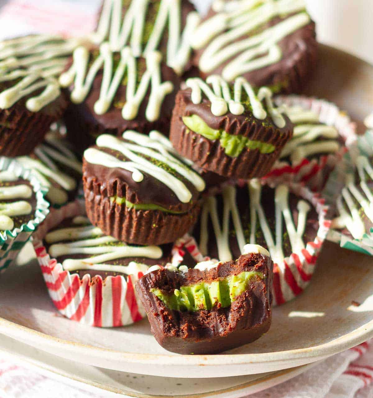 A plate filled with chocolate matcha cups with one half eaten cup.
