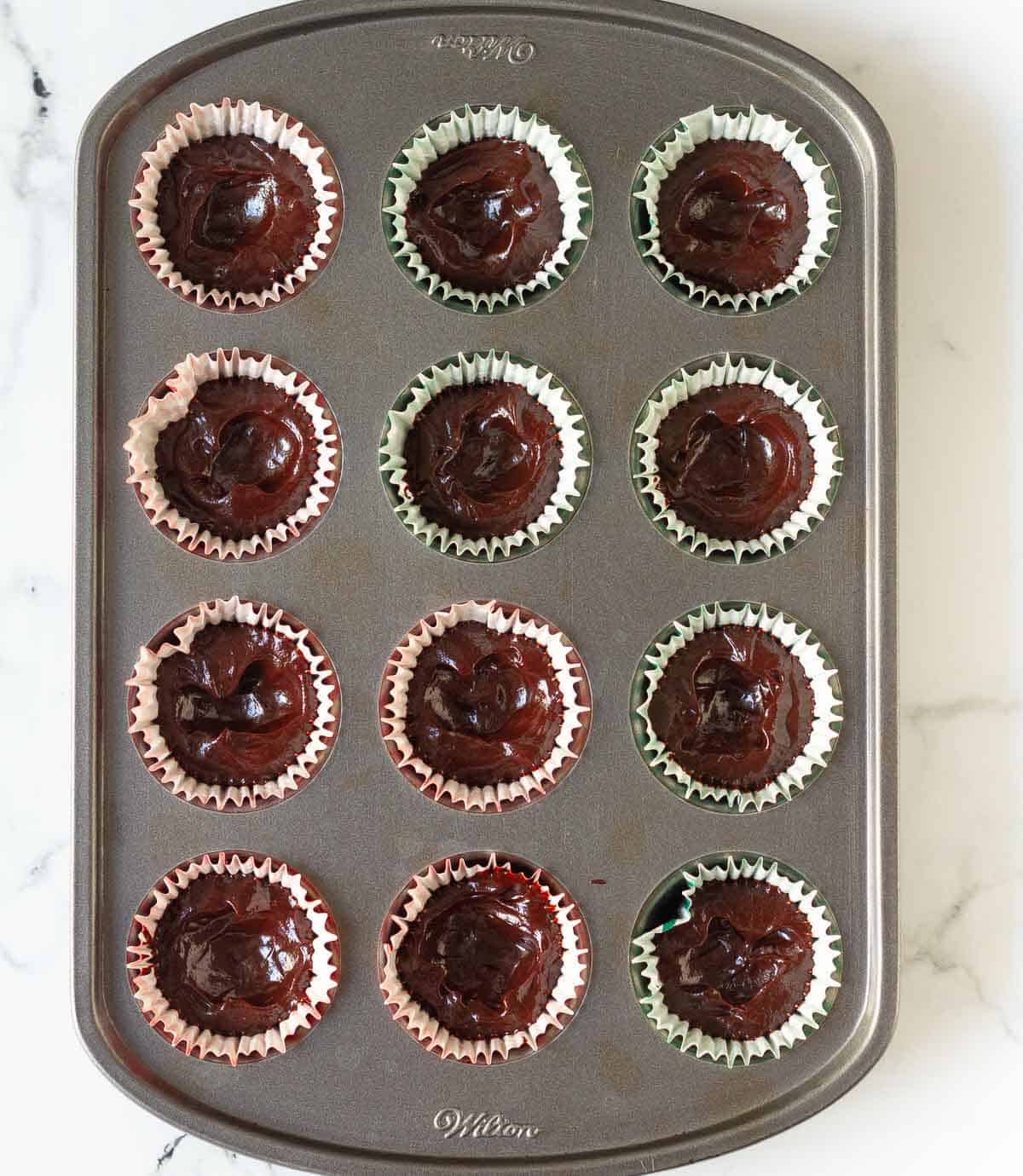 Melted dark chocolate in mini muffin lined tray.