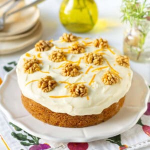 Eggless carrot cake with cream cheese frosting on a white platter.