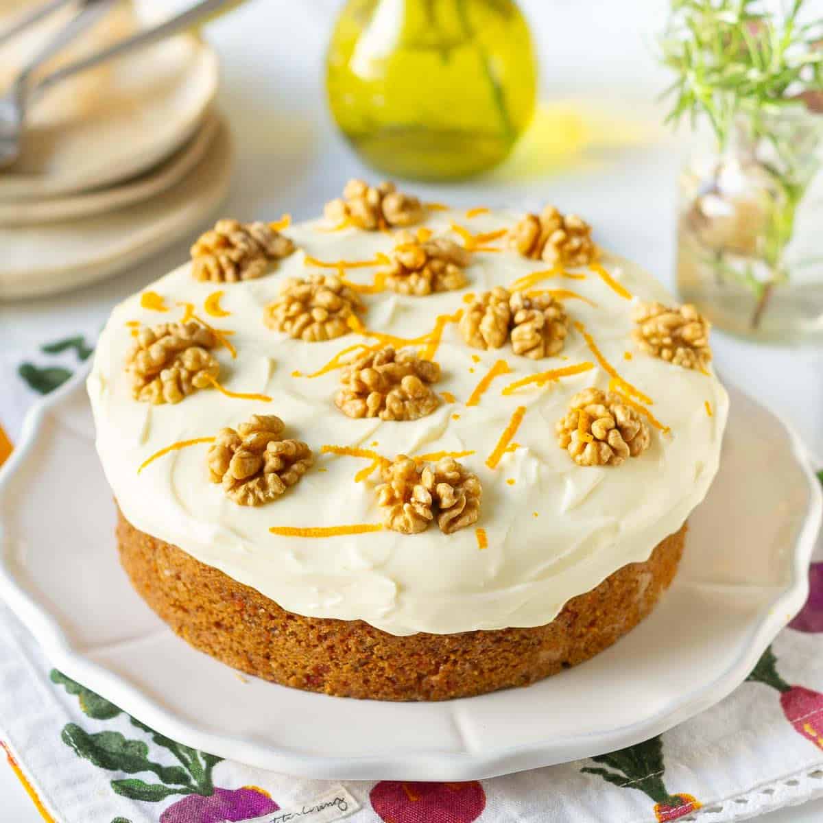 Eggless carrot cake with cream cheese frosting on a white platter.
