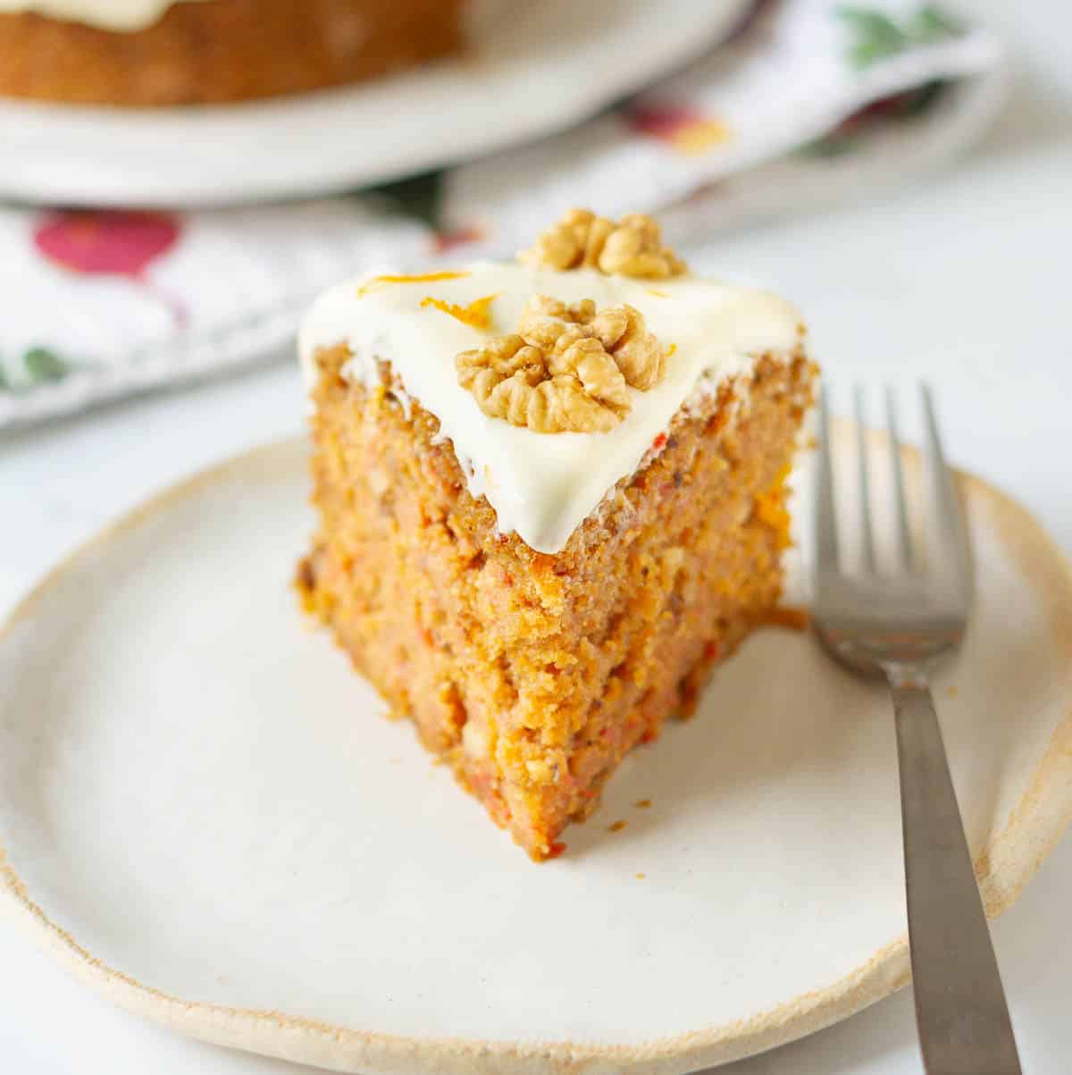 A slice of carrot cake on a small plate with a fork.