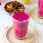 Mulberry mango smoothie in a glass on a small plate.