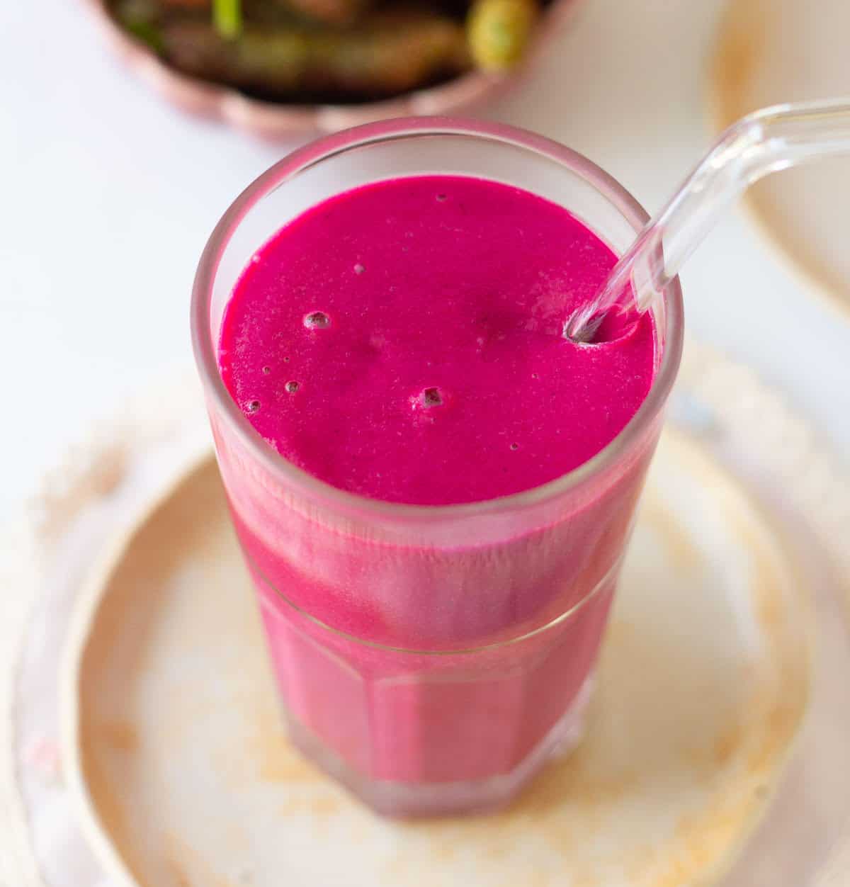 Mulberry smoothie in a glass with a glass straw.