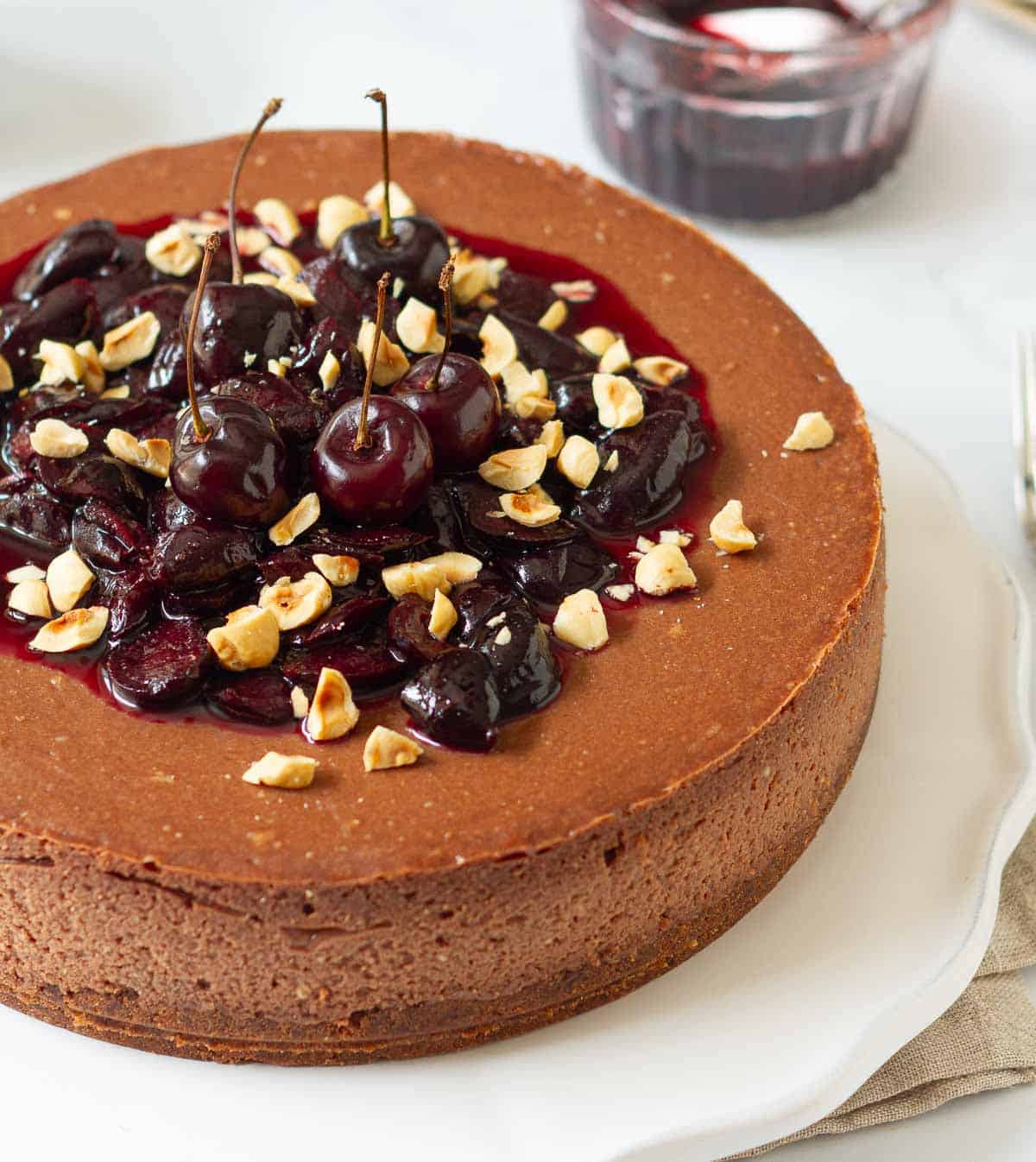 Chocolate cheesecake with cherry sauce and hazelnuts on top.