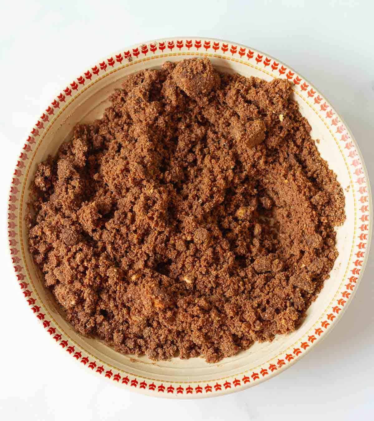A mixture of crushed cookies, butter, and cocoa powder in a bowl.