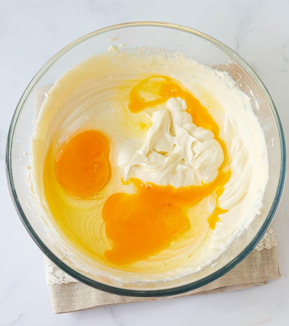 Eggs on top of cream cheese mixture in a mixing bowl.