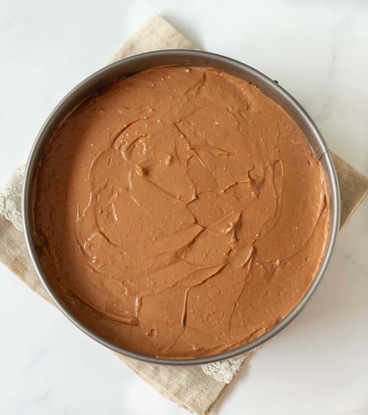 Chocolate cheesecake batter in a cake pan.