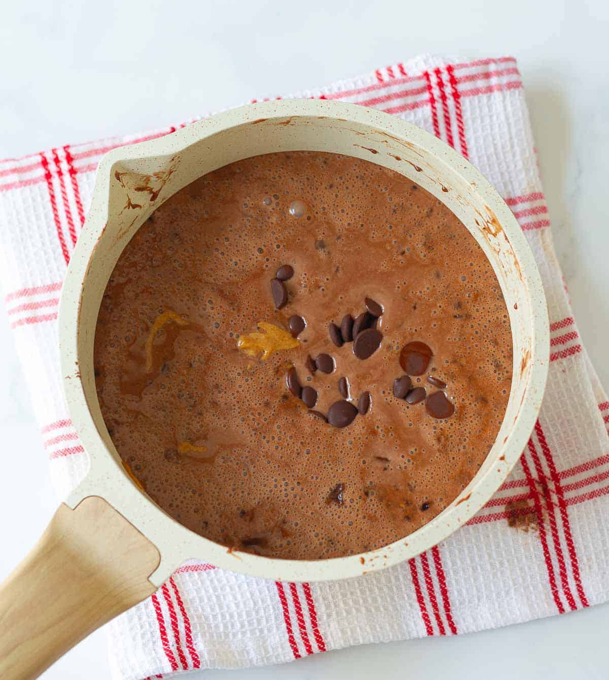 Chocolate and almond butter added to the cream mixture in a saucepan.