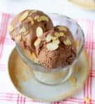 3 scoops of chocolate ice cream in a dessert cup with toasted flaked almonds on top.