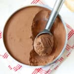 Ice cream in a pan with a scoop taken out with an ice cream scooper.
