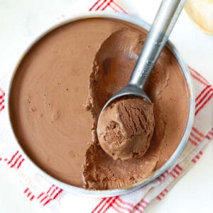 Ice cream in a pan with a scoop taken out with an ice cream scooper.