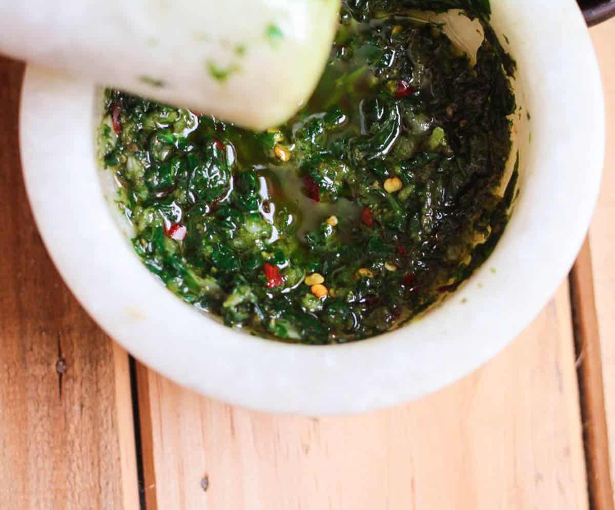 Garlic basil mixture in a mortar with a pestle.