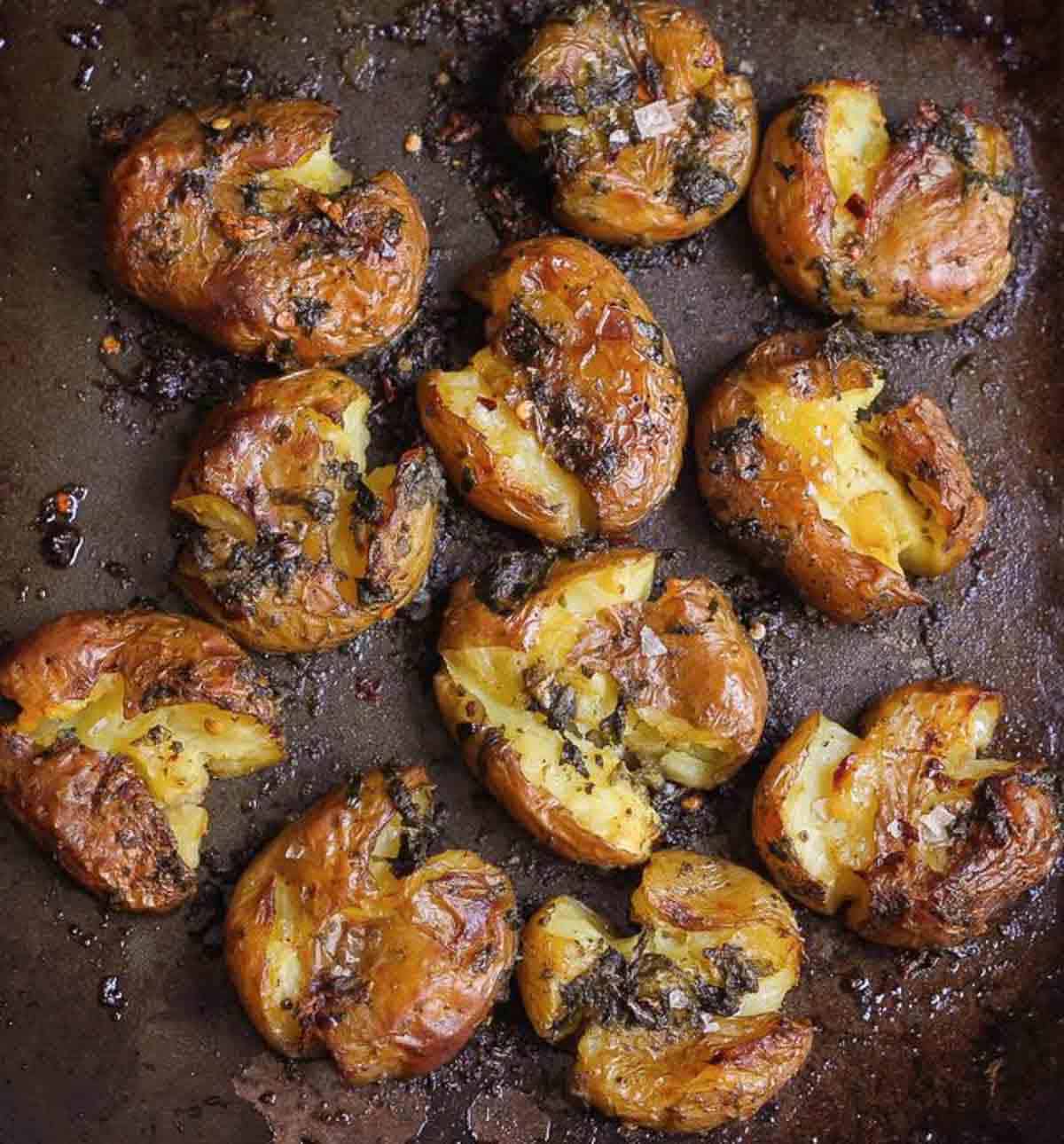 Smashed potatoes on a back baking tray.