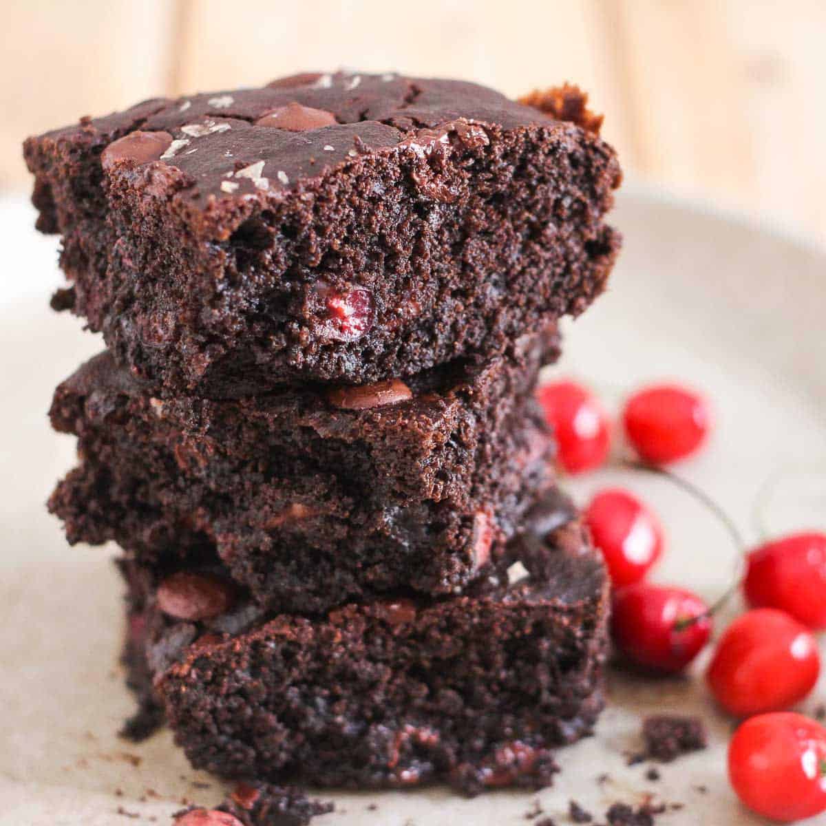 3 squares of chocolate cherry cake stacked on a platter.