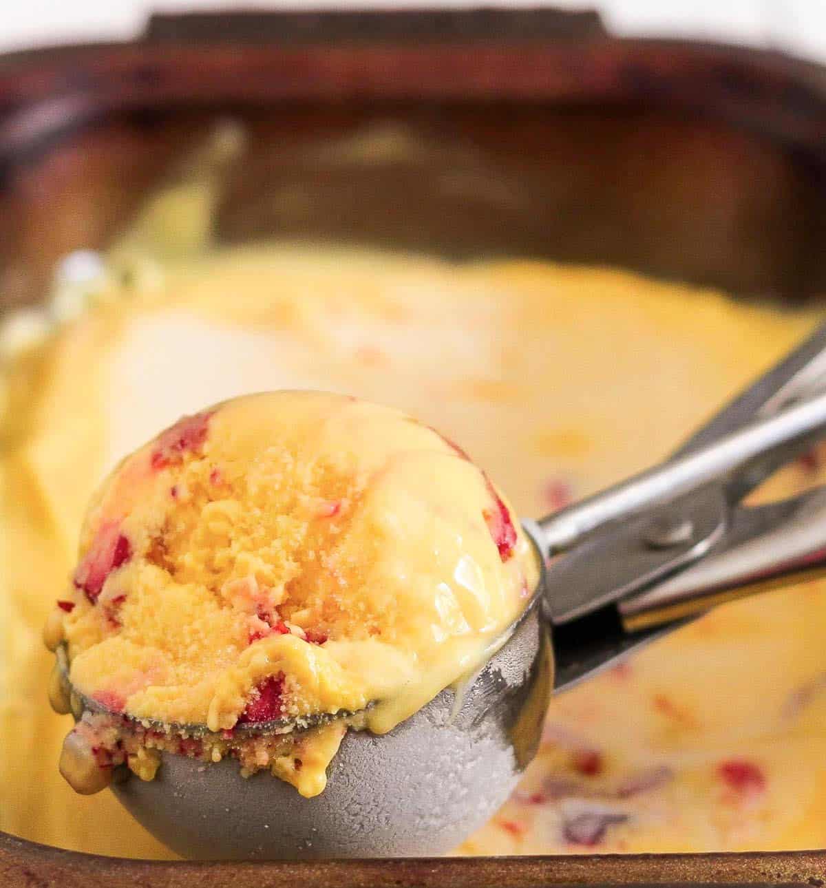 Scoop of mango froyo in an ice cream scoop.