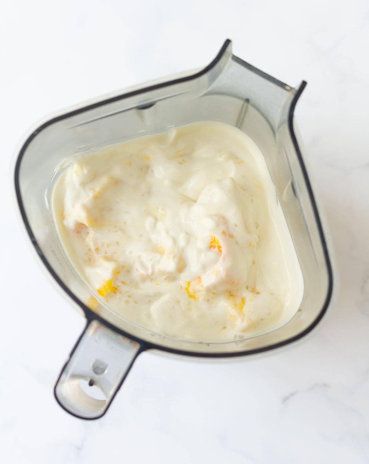 Yogurt, sugar, mango in a blender jar.