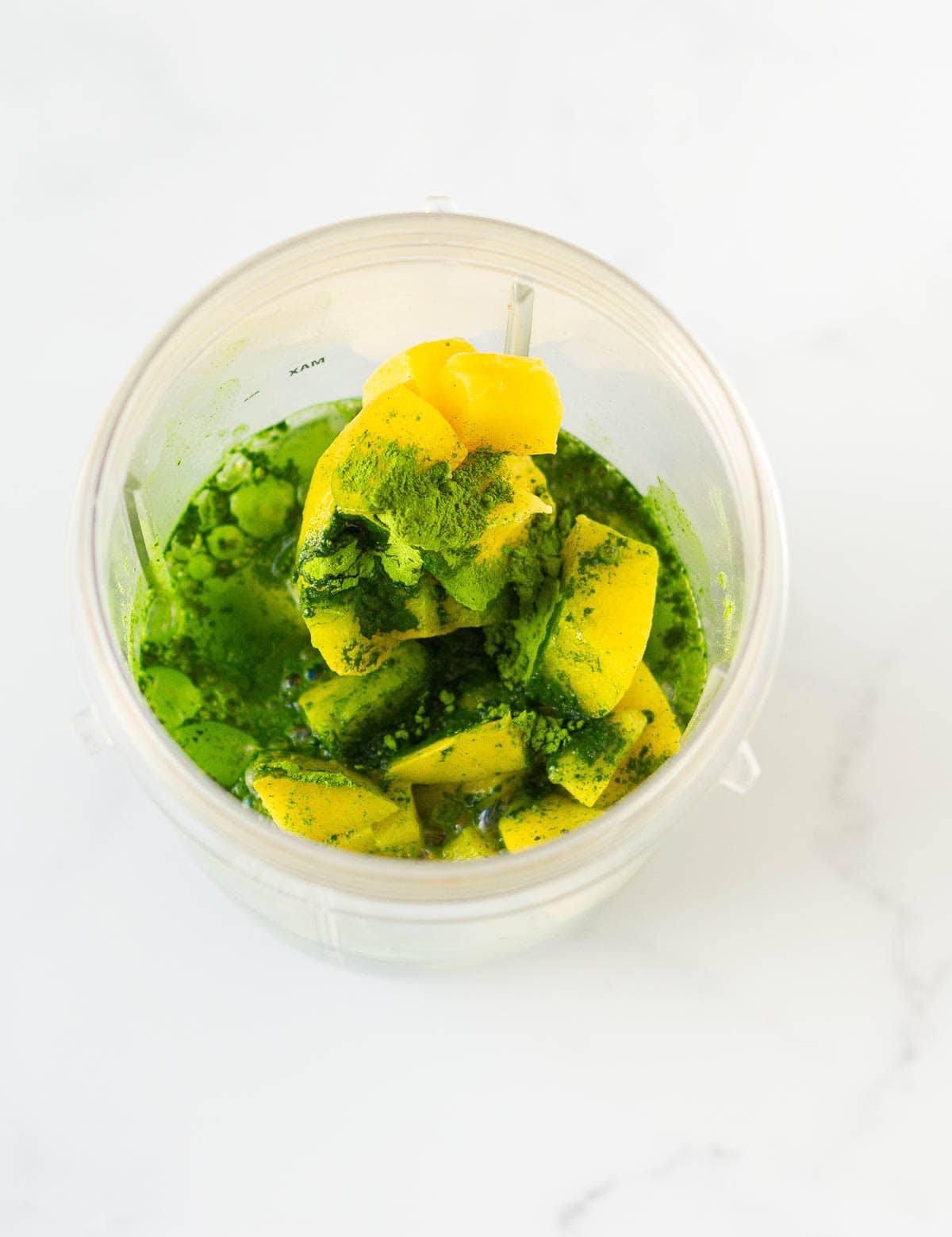 Matcha, mango, avocado, and coconut water in a blender jar.
