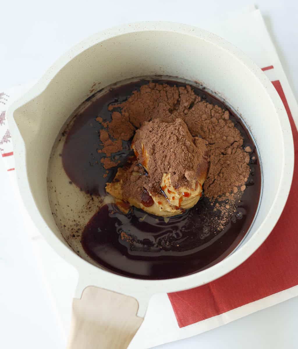 Cocoa powder, peanut butter, date syrup, coconut oil in a saucepan.